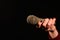 Woman hands holding dirty and dusty microphone on a dark background