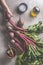 Woman hands holding fresh beetroot  with greens on rustic table with ingredients: oil, salt and garlic on dark concrete background