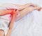 Woman with hands holding her crotch in pain. Bladder pain on bed at home