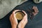 Woman hands holding mug of hot coffee, standing on wooden table with chocolate, coffee beans and sackcloth