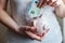 Woman hands holding pink piggy bank and putting money Euro