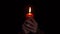 Woman hands holding single red wax candle that lights in the dark