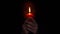 Woman hands holding single red wax candle that lights in the dark than blow it out.