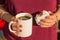 Woman hands holding traditional Argentinian breakfast coffee and alfajor with dulce de leche and powdered sugar. Selective focus.