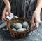 Woman hands holding wicker basket with Easter eggs on table. Happy Easter holiday, selective focus