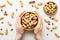 Woman hands holding a wooden bowl with close peanuts. Healthy food and snack. Vegetarian snacks of different nuts