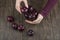 Woman hands holding a wooden bowl with healthy purple plums