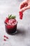 Woman hands holds currant berries for preparation of fresh ice cold fruit cocktail drink in glass with rosemary leaf