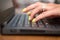 Woman hands on a laptop keyboard on brown table. She working, typing something. Yellow  nail polish on her fingers