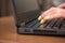 Woman hands on a laptop keyboard on brown table. She working, typing something. Yellow nail polish on her fingers