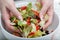 The woman hands mixes salad