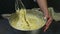 Woman hands mixing by whisk yeast dough with whisked yolks and whipped cream