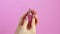 Woman hands open rotate lipstick close up pink background