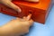 Woman hands opening lock on orange metal box on blue table