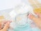 Woman hands packaging transparent glass tea cup with bubble wrap on a white blue checkered tablecloth. Material for packing