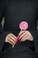 Woman hands with perfect nail polish holding some pink and white lollypops