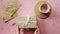 Woman hands putting a Christmas gift wrapped in craft paper with white bow on top view on wood pink table, flat lay