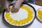 Woman hands putting pieces of apricot on the raw dough close up