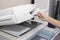 Woman hands putting a sheet of paper into a copying device or printer in the office