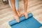 Woman hands rolled up yoga mat on gym floor in yoga fitness training room. Home workout woman close up hands rolling