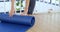 Woman hands rolled up yoga mat on gym floor in yoga fitness training room. Home workout woman close up hands rolling foam yoga gym