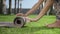 Woman hands rolling up yoga mat after training in park.Girl folding mat on grass