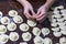 Woman hands sculpting dumplings. Step-by-step process of making homemade varenyky stuffed with mashed potatoe on a dark table. Top