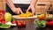 Woman hands slicing yellow pepper halves for a vegetables salad