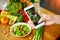 Woman hands take smartphone food photo of vegetables salad with tomatoes and fruits. Phone photography for social media or