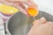 Woman hands to egg shells and separate egg yolk