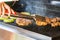 Woman hands turning juicy chicken steaks and grilled zucchini slices prepared on a modern garden grill