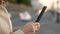 Woman hands using smartphone close up against evening road and cars headlights