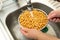 Woman hands washing fresh chickpeas under the running water, healthy food concept