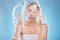 Woman, hands and water splash for washing face grooming, healthcare wellness or self care hygiene on studio blue