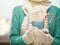 Woman hands in white woolen mittens holding a cozy cup with hot cocoa, tea or coffee. Winter and Christmas time concept.