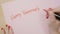 Woman hands writing happy valentines day in capital letters on pink paper with a red marker -