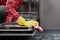 The woman hands in yellow gloves cleaning dishwasher panel with pink rag in kitchen.close up