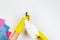 Woman hands in yellow rubber gloves click on white spray bottle with liquid detergent on white background. Housework