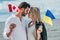 Woman and handsome man holding canadian and ukrainian flags