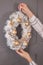 Woman hang modern rustic christmas wreath on wall