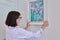 Woman hanging floral birds art framed at home on the wall