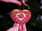 A woman hanging a red cross stitch Christmas Timeless Elegance ornament on to a Christmas tree.