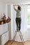 Woman hangs white curtains on the curtain rod