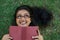 Woman, happy and reading book on grass, literature and smiling for fiction or fantasy story. Female person, nature and