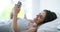 Woman, happy and scroll phone in bed for reading funny social media notification, chat or mobile app at home. Cellphone