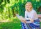 Woman happy smiling blonde take break relaxing in garden reading poetry. Girl sit bench relaxing with book, green nature