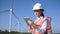 Woman with hard hat against wind turbine