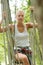 Woman in harness crossing rope bridge in forest