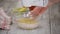 Woman has adding the chicken eggs and is stirring the baking dough in a glass bowl. Home baking concept.