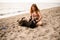 woman has fun and plays with her dog on the sandy beach